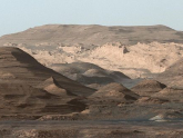 An image taken by the Curiosity Rover MastCam instrument shows layered sedimentary rocks composing Mount Sharp. The rover has been driving from the floor of Gale crater up through the rocks within these hills in order to understand how the rocks